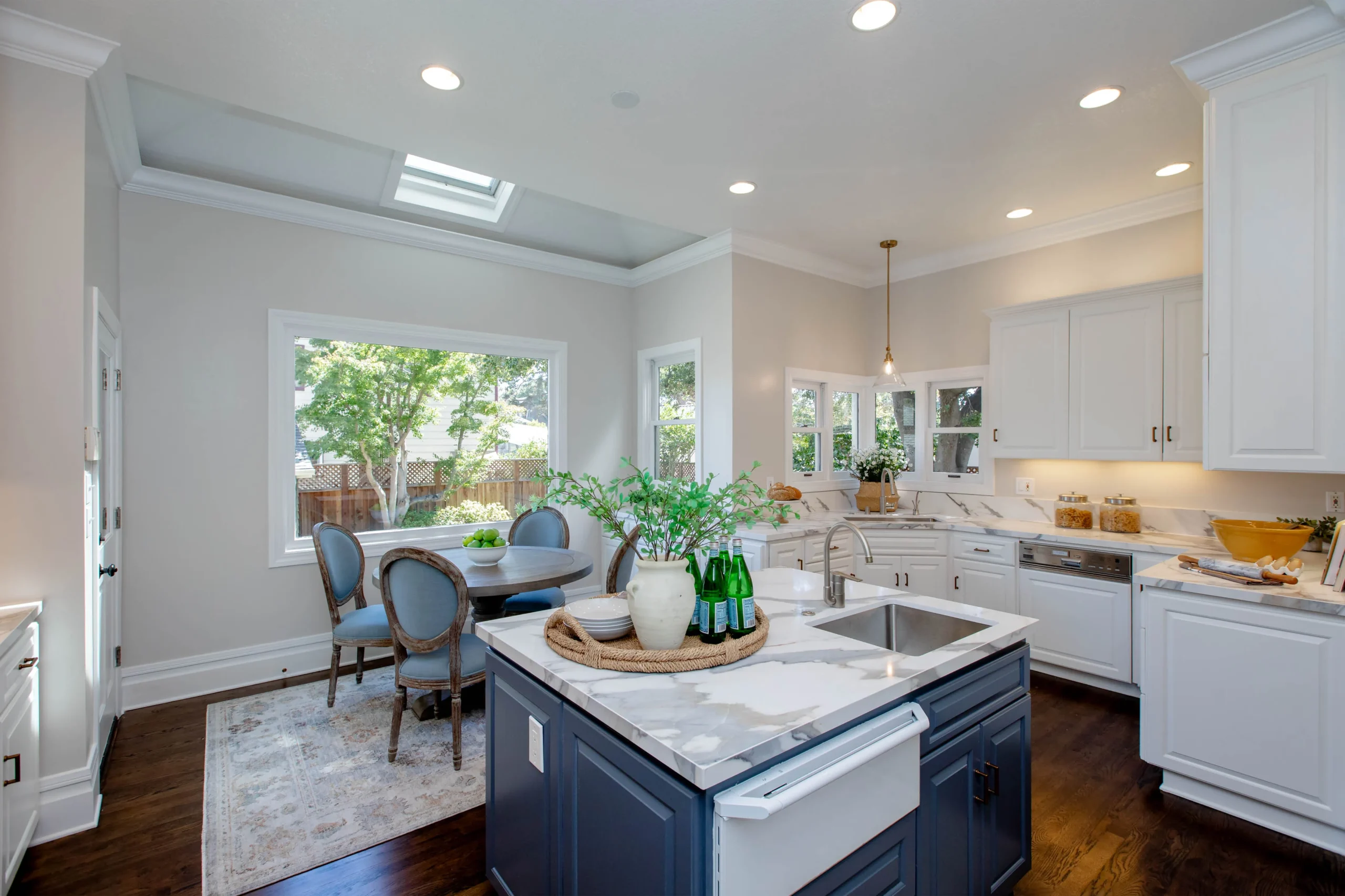 Modern kitchen with white cabinets and a blue island, bright and spacious design.
