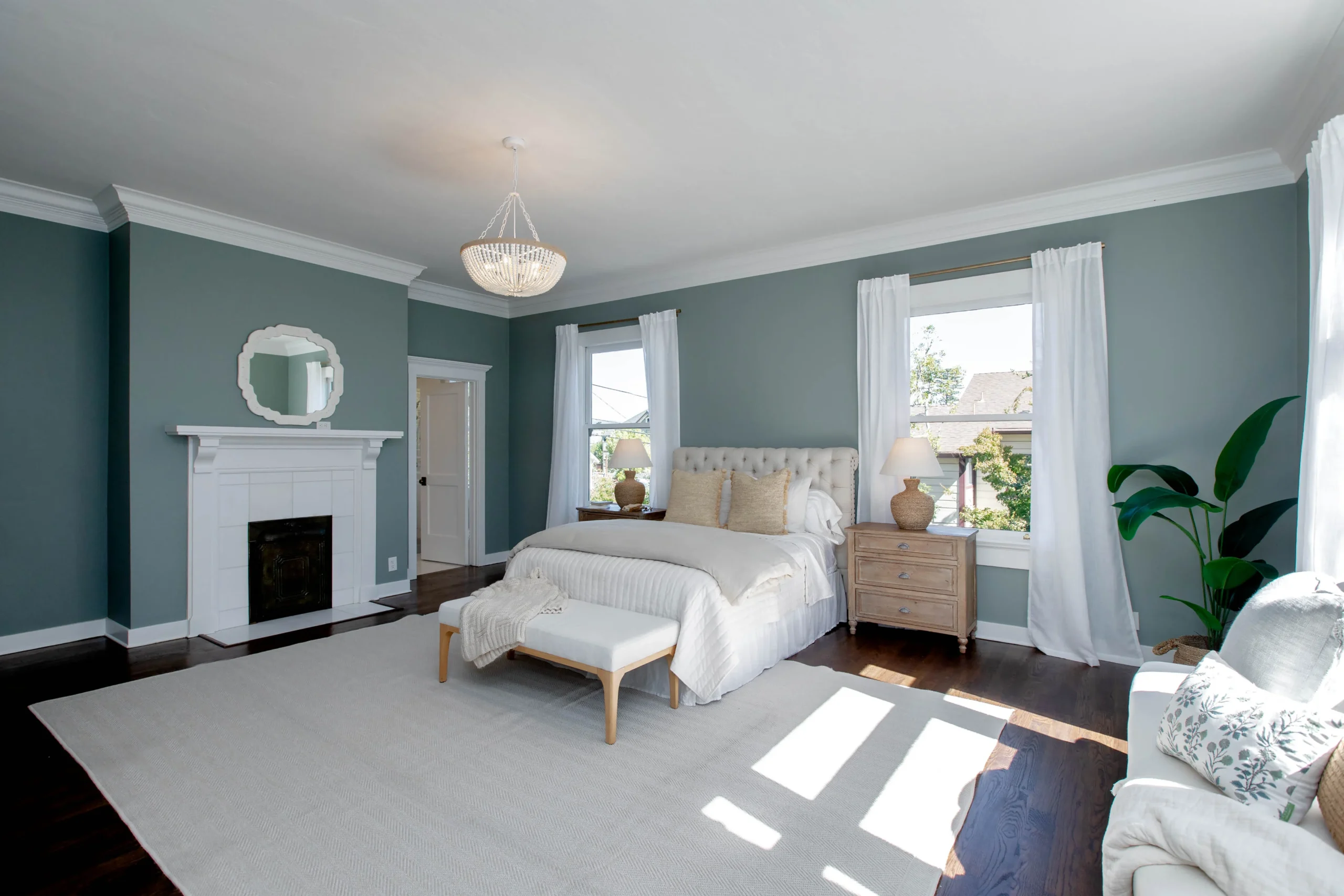 Elegant bedroom with blue walls, white bedding, and natural light from windows.
