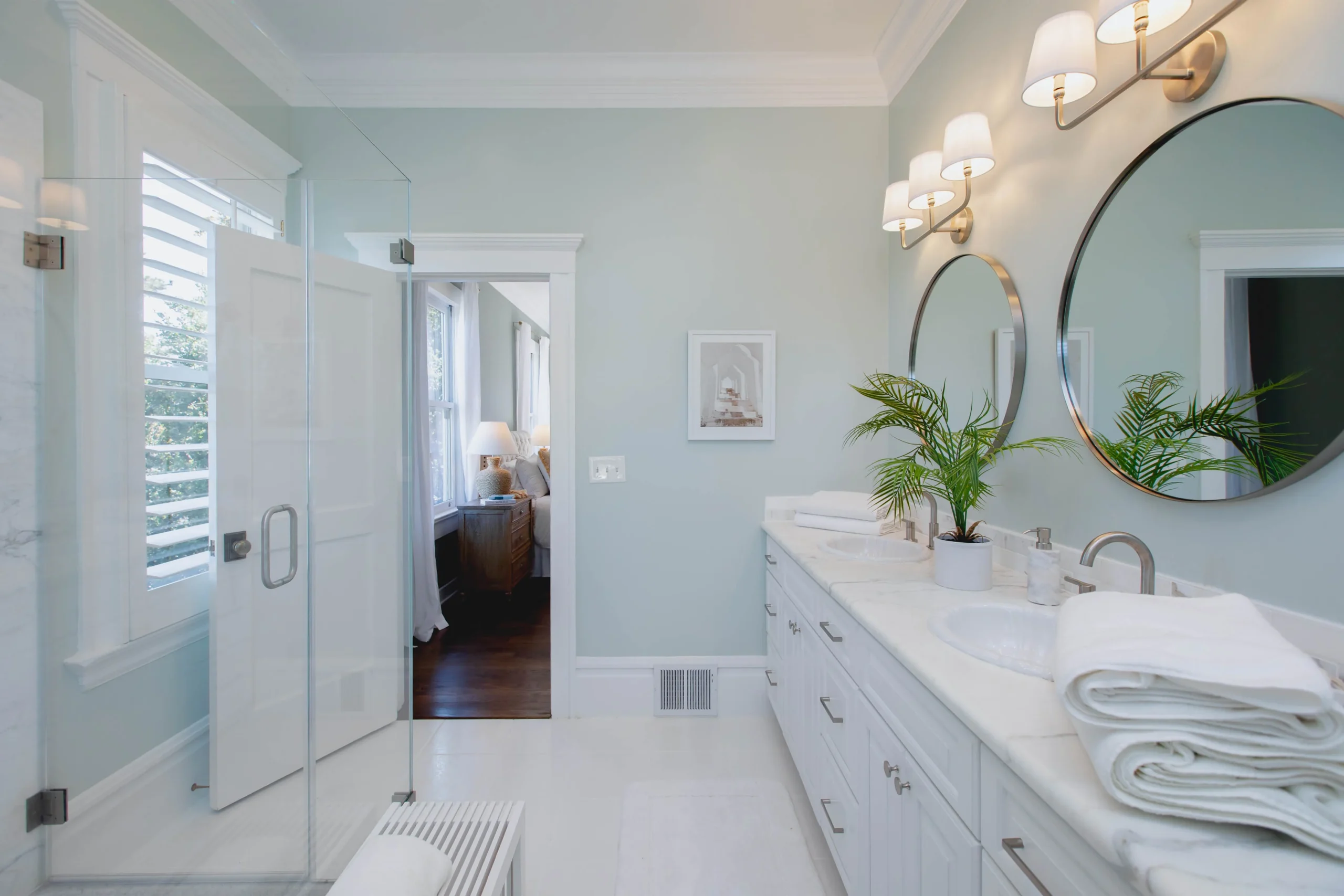 Bright modern bathroom with double vanity and glass shower enclosure.
