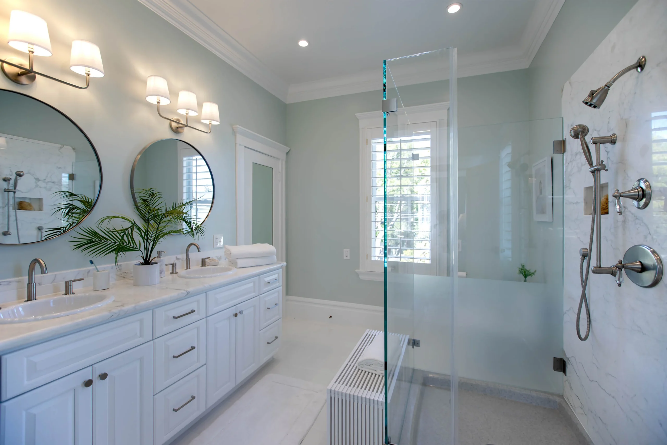Modern bathroom with double vanity, walk-in shower, and light blue walls.
