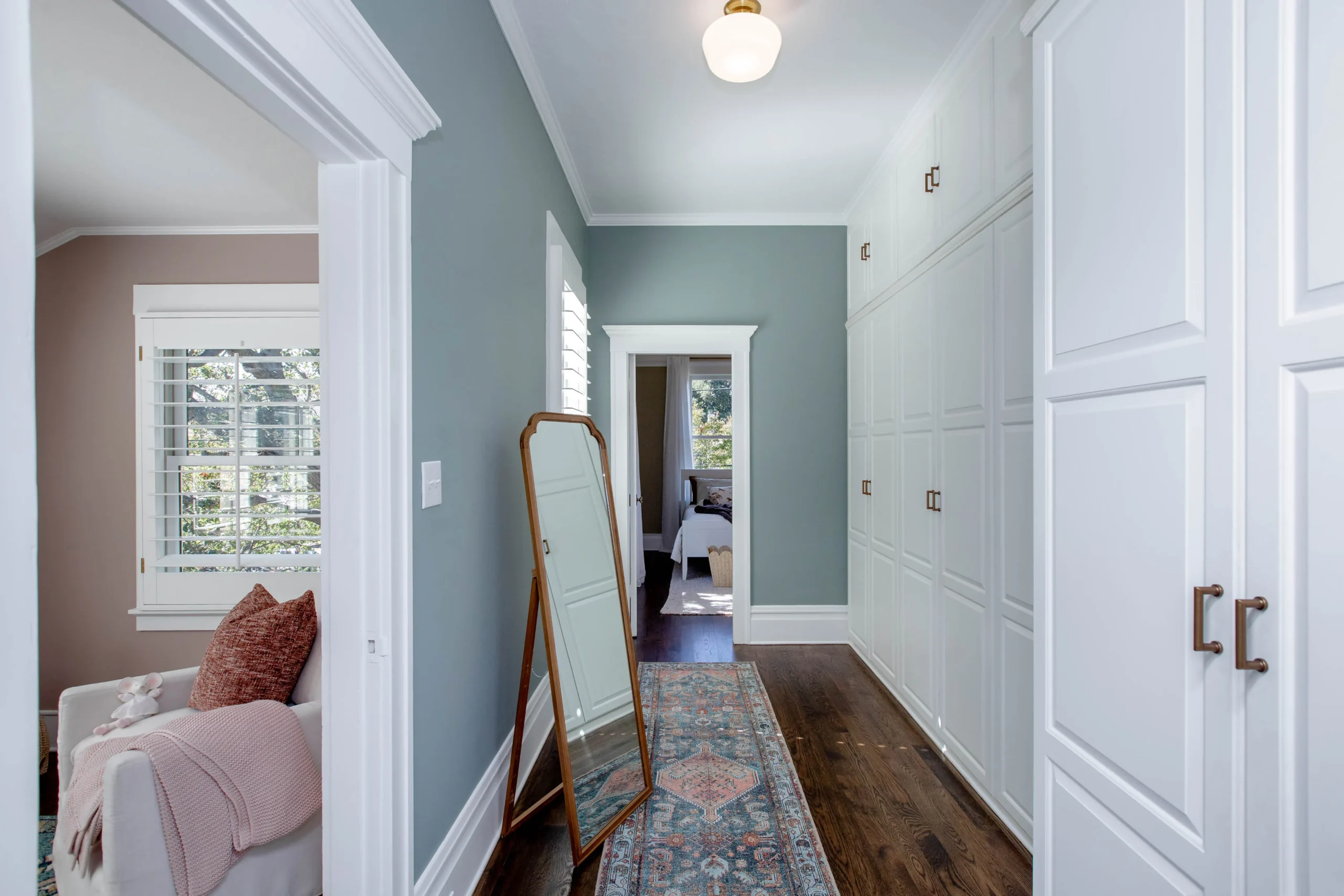 Bright hallway with built-in white cabinets and hardwood floor.