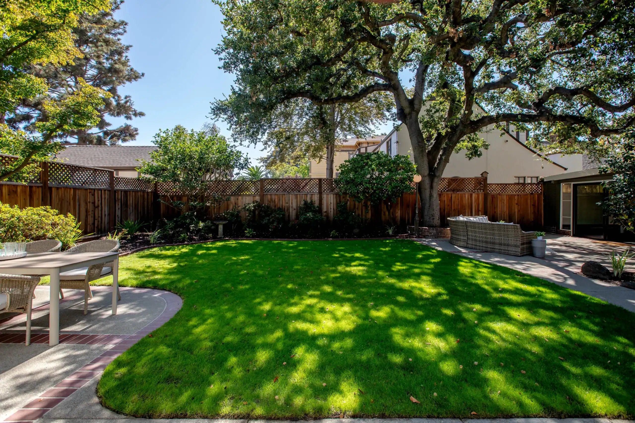 Beautiful backyard with lush green lawn and mature trees in a suburban setting.
