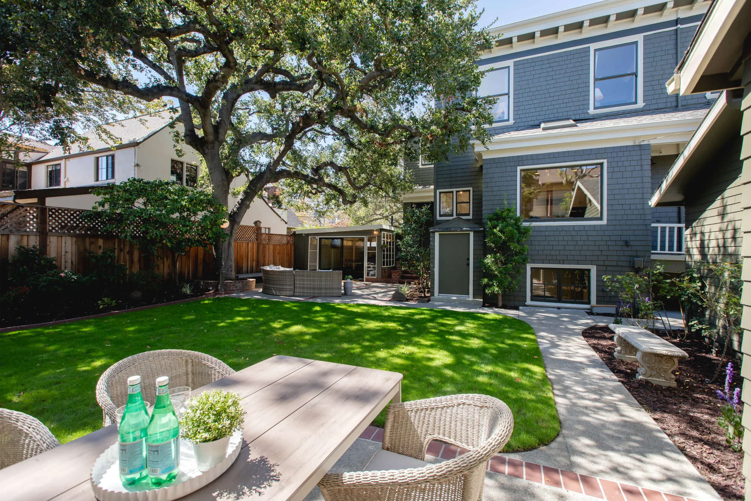 Beautiful backyard with lush green lawn, large tree, and modern house exterior.