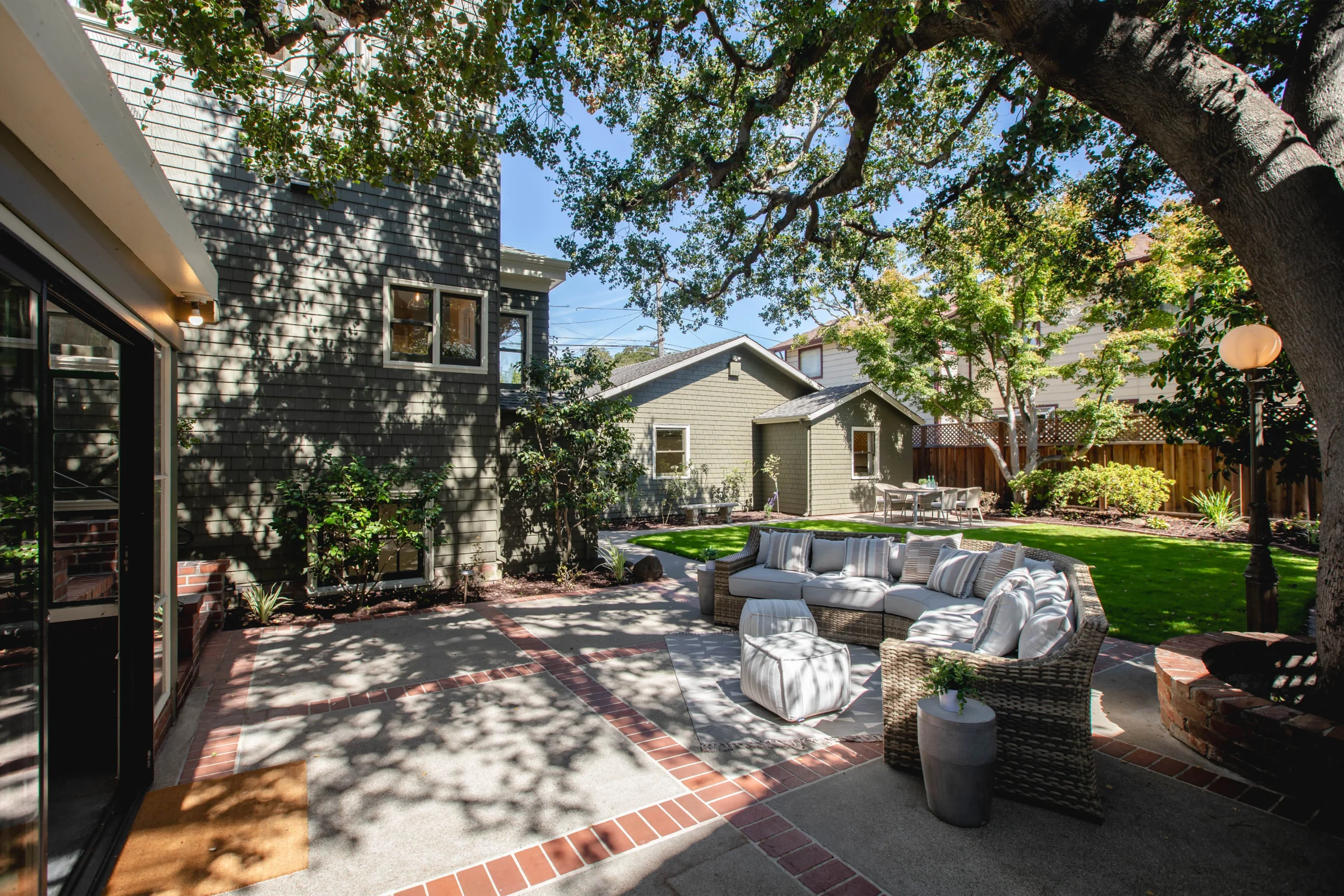 Beautiful backyard patio with outdoor seating and lush trees in a residential garden.