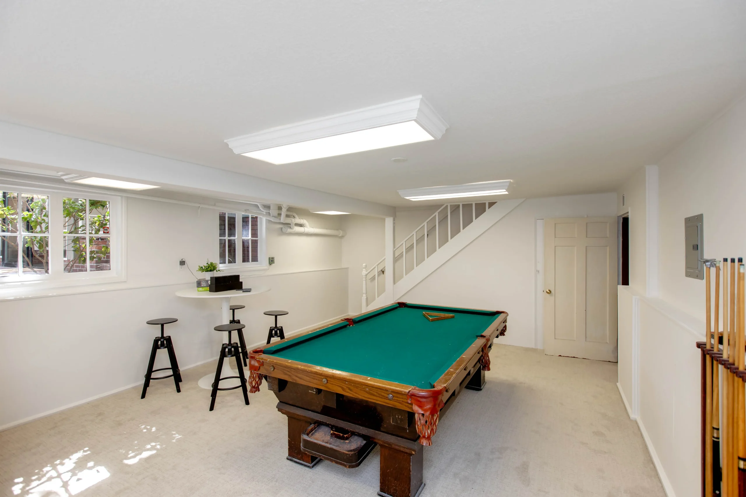 Spacious basement game room with pool table and seating area.