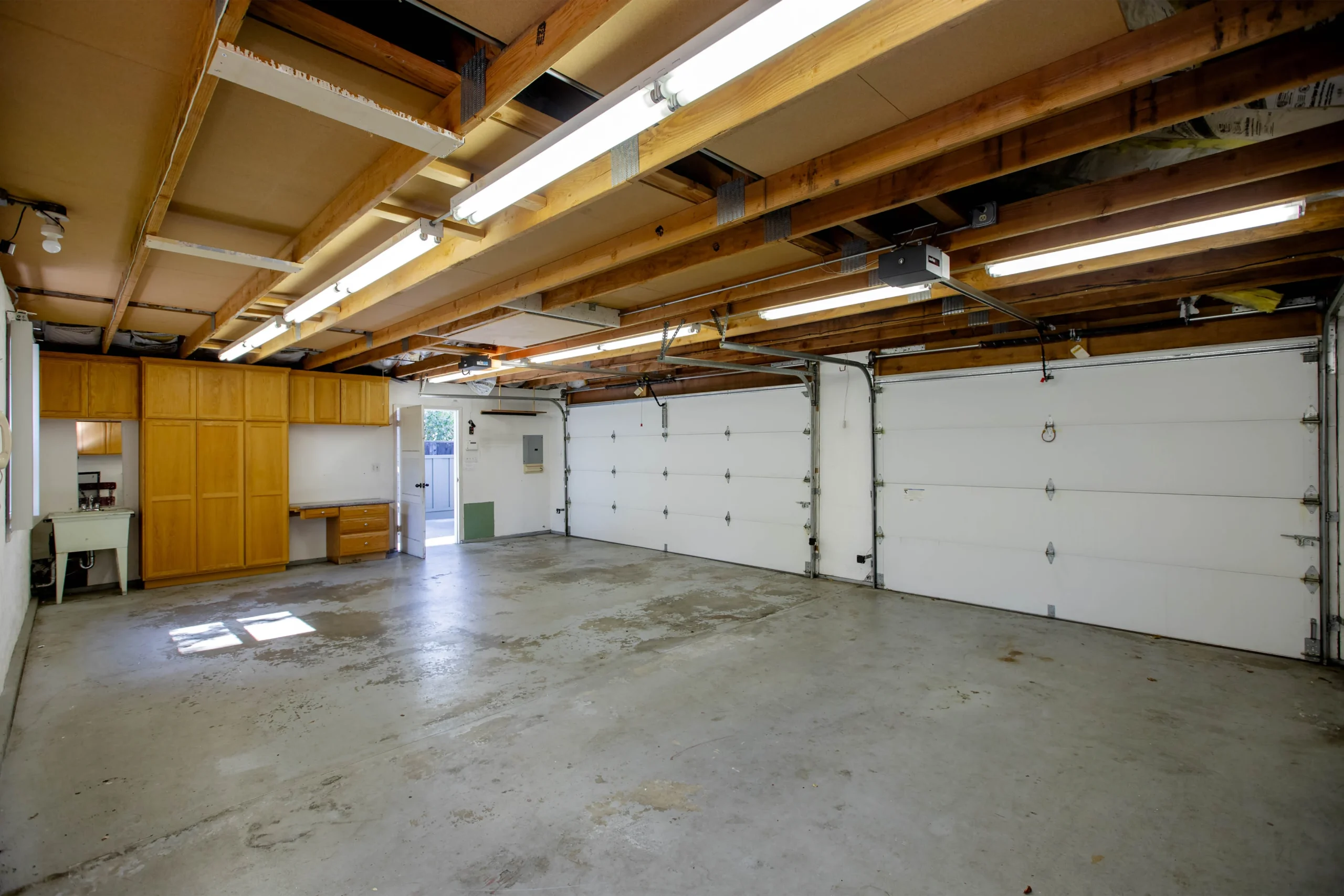 Spacious empty garage with concrete floor and wooden ceiling beams.