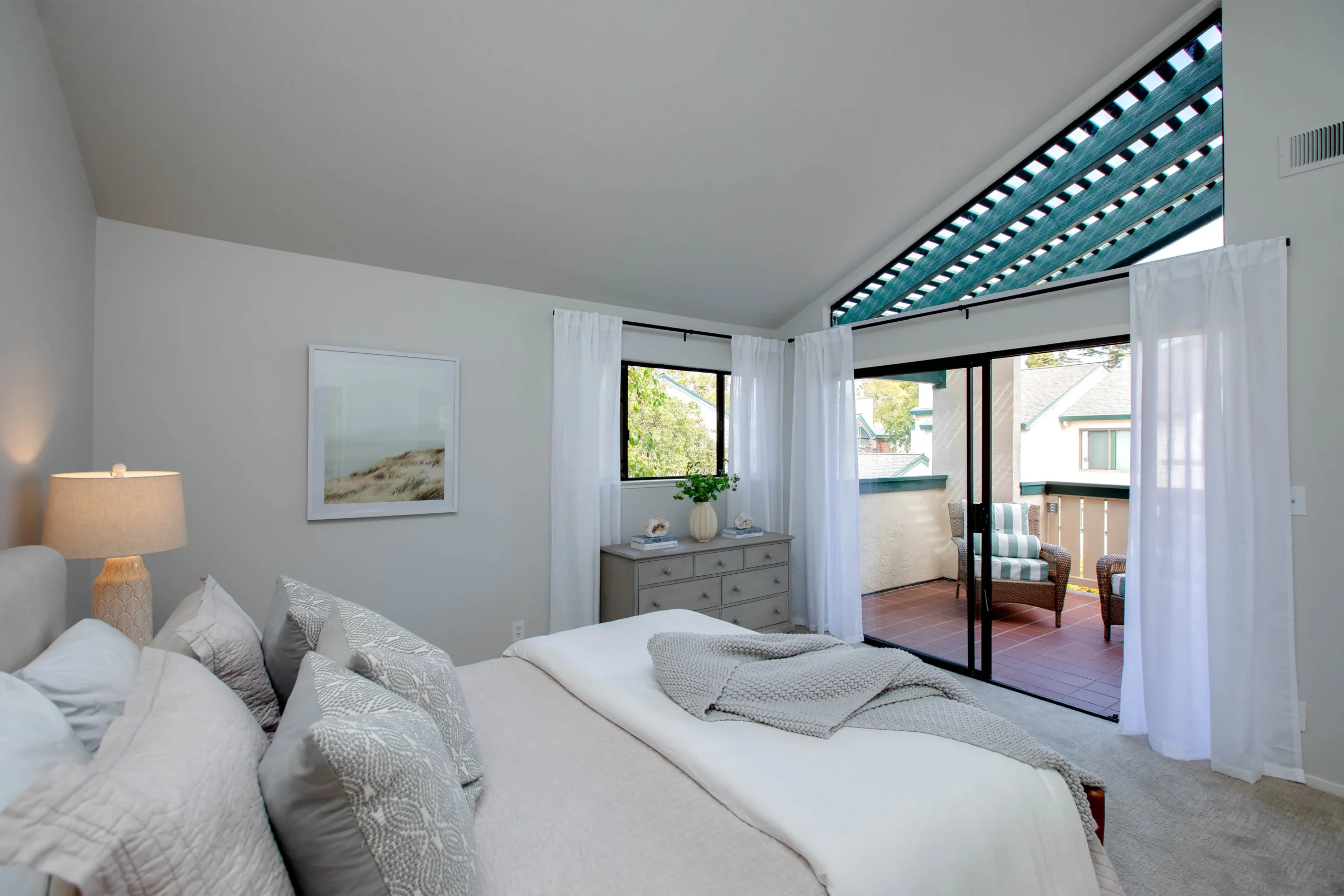 Bright bedroom with large windows and white curtains, modern decor.