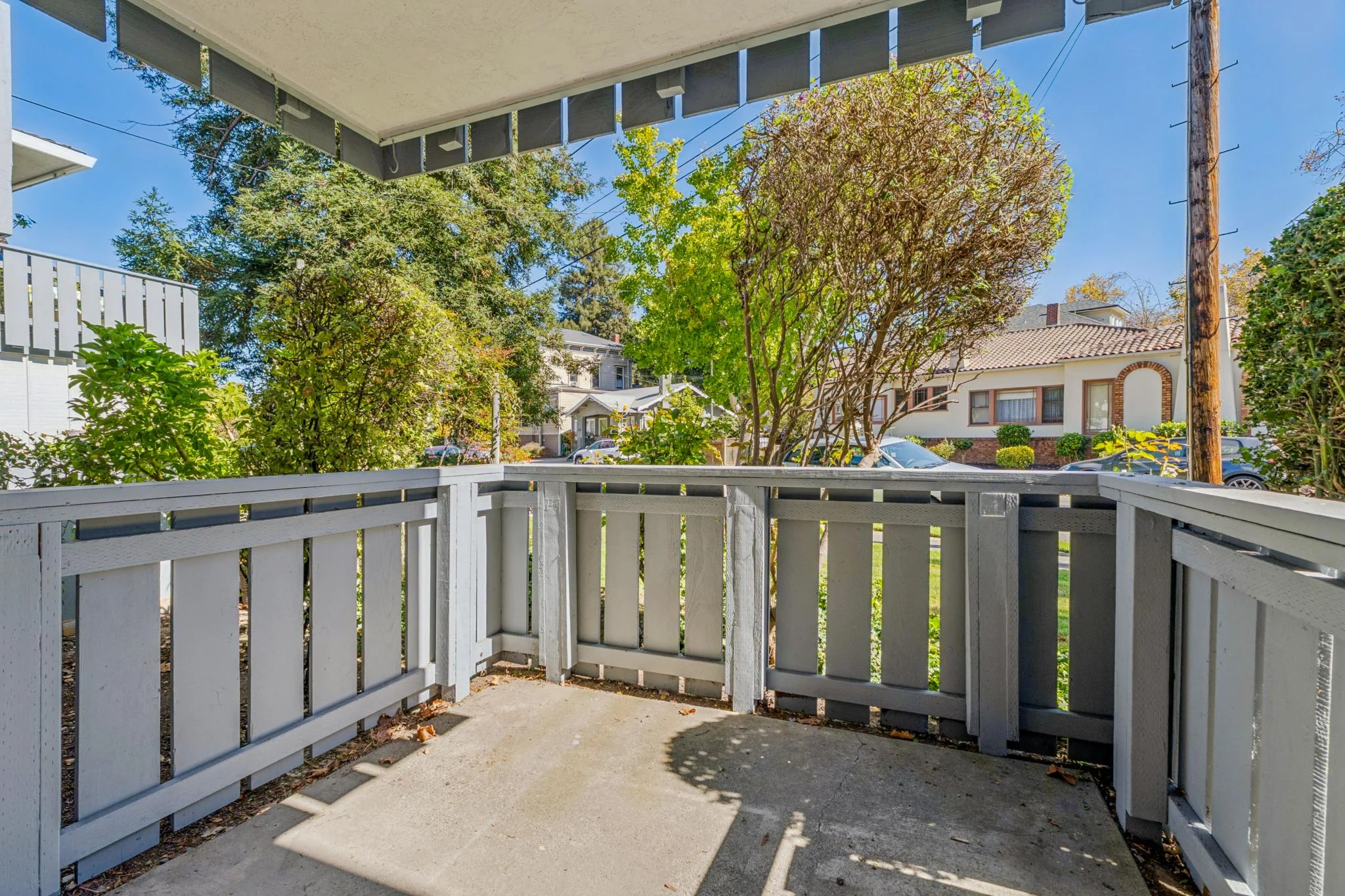 Cozy balcony with white railing and lush greenery in the background.