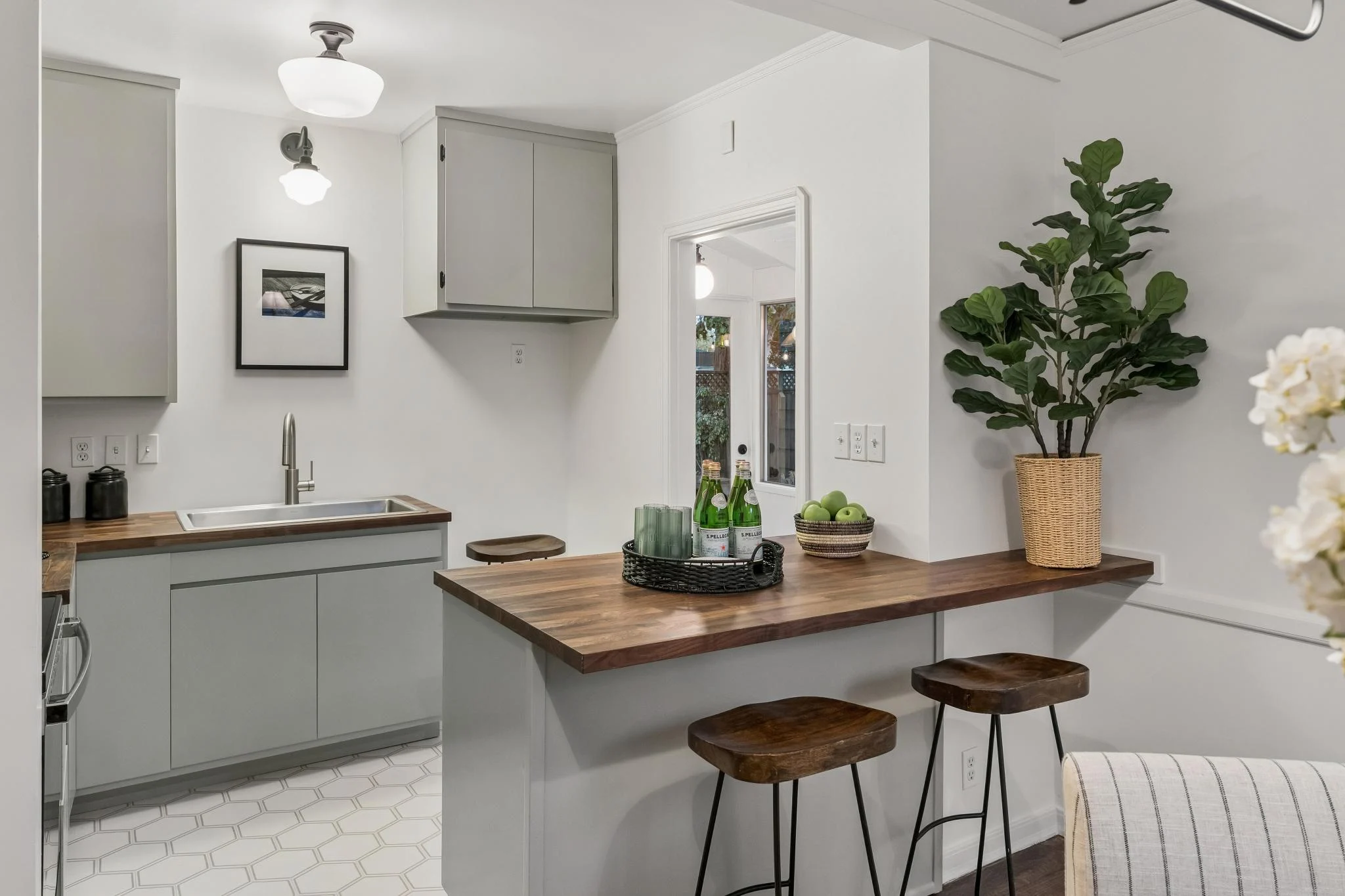 Modern kitchen with white cabinets and wooden countertop with bar stools.