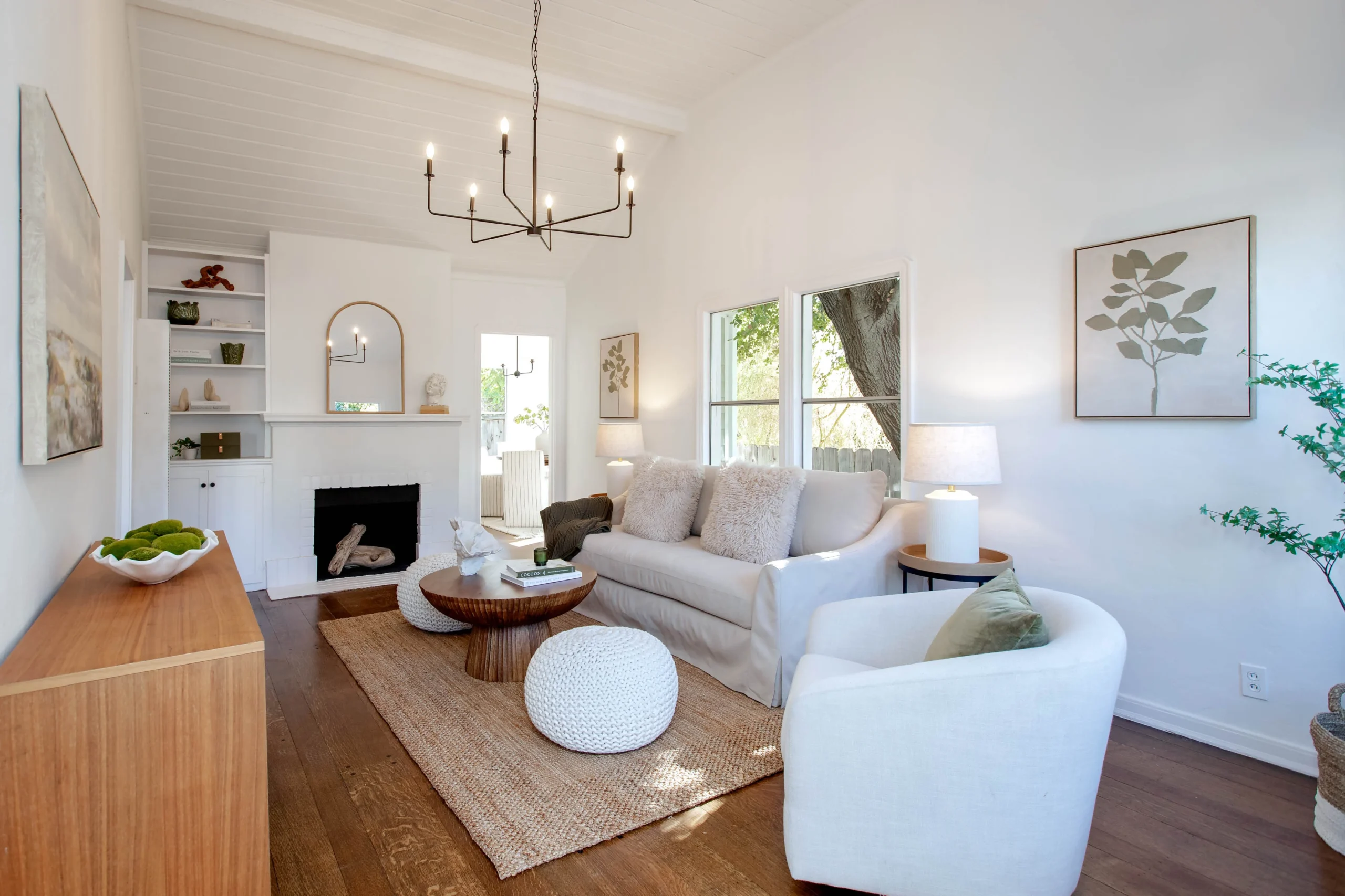 Bright living room with white sofa, armchair, and natural light from large windows.