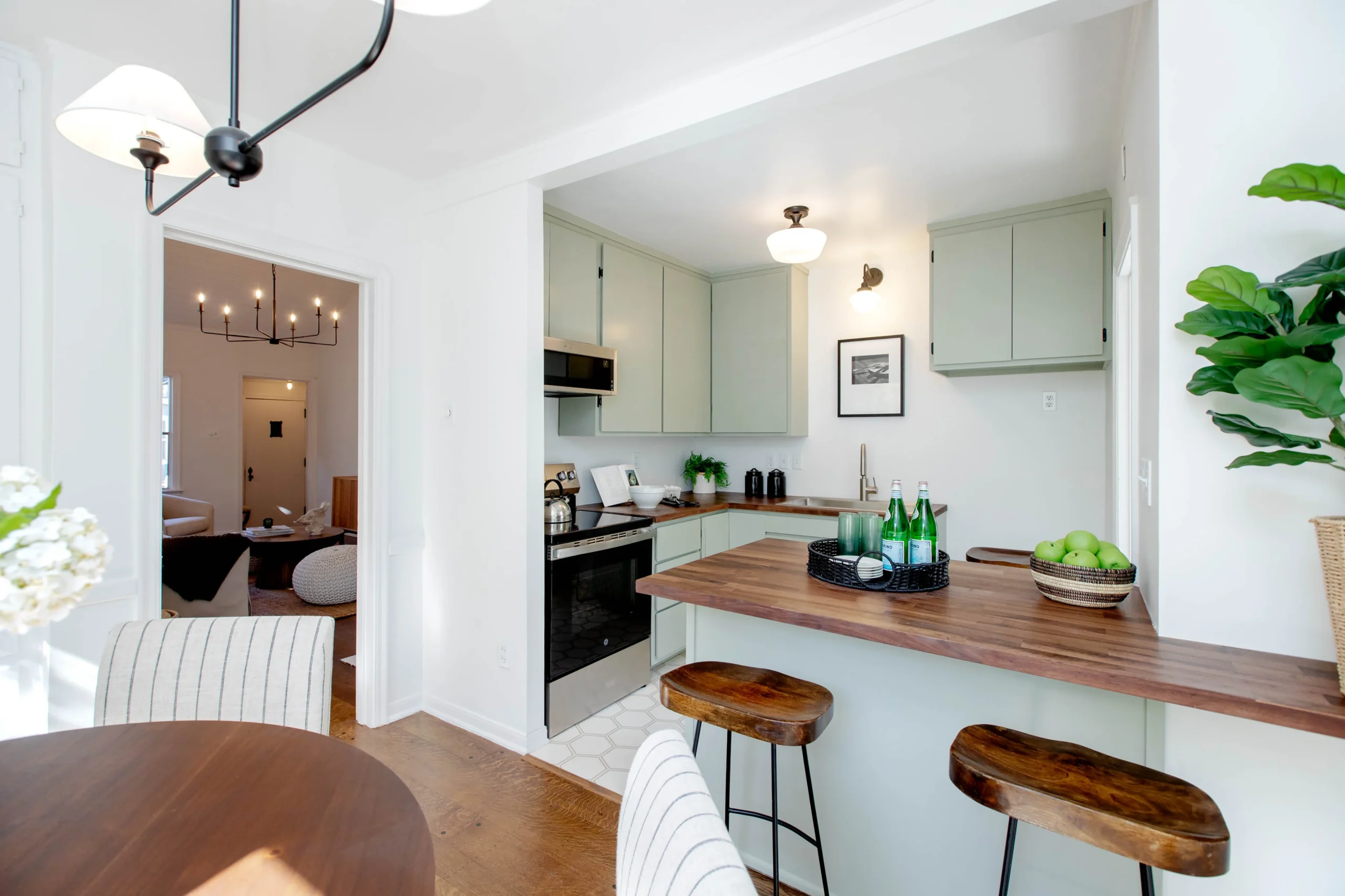 Modern kitchen with light green cabinets and wooden accents.