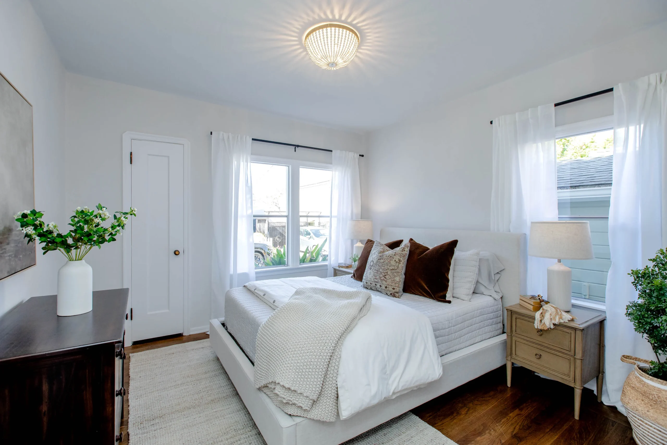 Bright bedroom with white walls, large windows, and cozy decor.